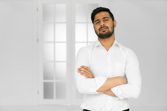 Indian Handsome Young Man Standing With Hands Folded Against White Background