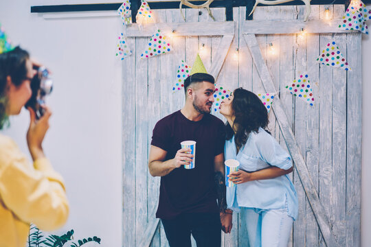 Funny girlfriend and boyfriend posing on common photo during birthday party on decorations background while photographer making picture,woman and man making image during celebration entertaining