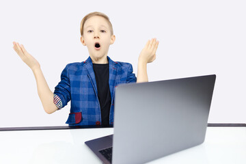 the boy in the jacket is surprised sitting at the computer
