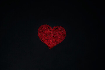 Red heart made of sequins on a black background.