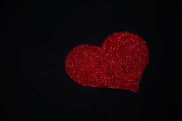 Red heart made of sequins on a black background.