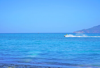 turquoise sea with a white boat that rushes through the waves, leaving a white, foam trace. For travel agencies.