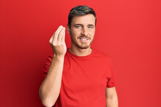 Handsome caucasian man wearing casual red tshirt doing italian gesture with hand and fingers confident expression