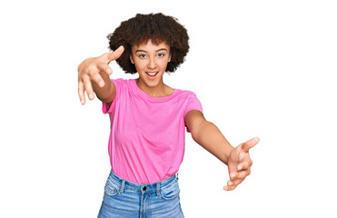 Young hispanic girl wearing casual clothes looking at the camera smiling with open arms for hug. cheerful expression embracing happiness.