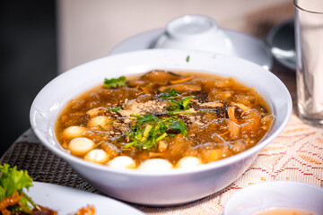 Chinese style soup or braised fish maw in red gravy with eggs, mushroom, and bamboo shoot in white bowl. Braised Fish Maw in Red Gravy with crab in bowl.
