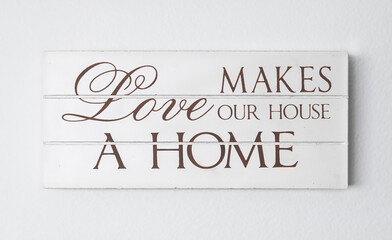 "Love makes our house a home" inspirational and decorative white wooden plaque.