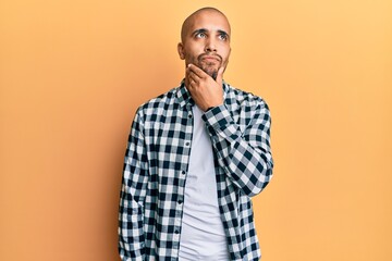 Fototapeta premium Hispanic adult man wearing casual clothes thinking concentrated about doubt with finger on chin and looking up wondering