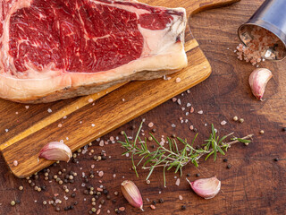Fresh raw sashi beef steak with rosemary, himalayan salt, garlic and black pepper grains, ready to be cooked