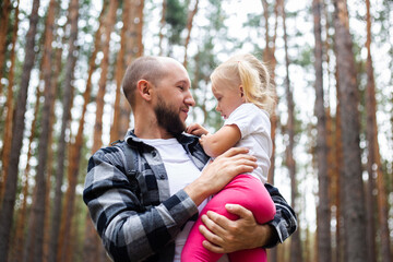 Dad holds the baby in his arms while hiking in the woods. Family hike to the mountains or forest
