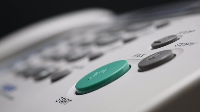 Close Up Of Male Finger Presses The Start Button On White Fax On Black Bokeh Background.