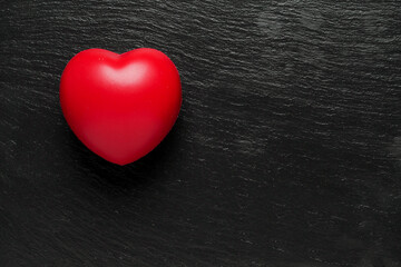 Red heart on dark stone surface, copy space for a message. Saint Valentine theme background.