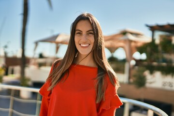 Young hispanic woman smiling happy standing at the city.