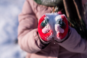 child hands holding a red heart with snow