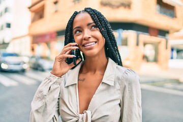Fototapeta premium Young african american woman smiling happy talking on the smartphone at the city.