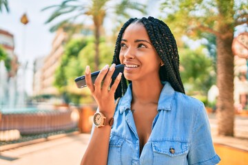 Young african american woman smiling happy sending voice message using smartphone at the park.