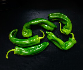 unevenly shaped green Italian peppers on dark background