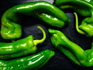 unevenly shaped green Italian peppers on dark background