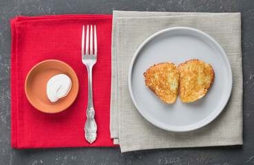 Potato pancakes, fork, sour cream, on the table