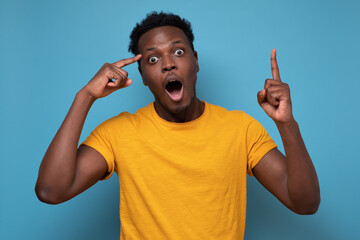 Young handsome african man pointing with finger up having great idea for start up. Studio shot on...