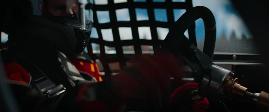 CU View of sports car driver in protective overalls racing on a speedway. Fast speed, motorsport. Daytime shot. Shot with 2x anamorphic lens