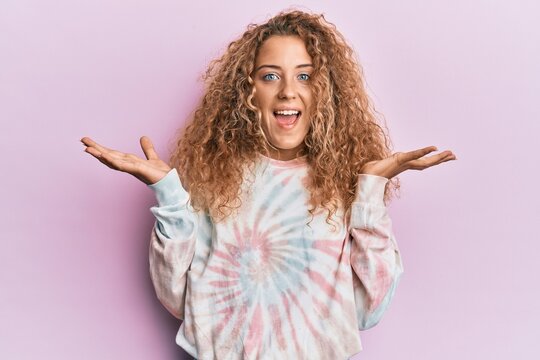 Beautiful caucasian teenager girl wearing casual tie dye sweatshirt celebrating victory with happy smile and winner expression with raised hands