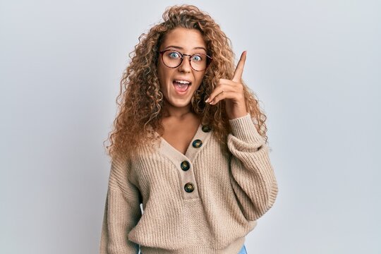 Beautiful caucasian teenager girl wearing casual clothes and glasses pointing finger up with successful idea. exited and happy. number one.