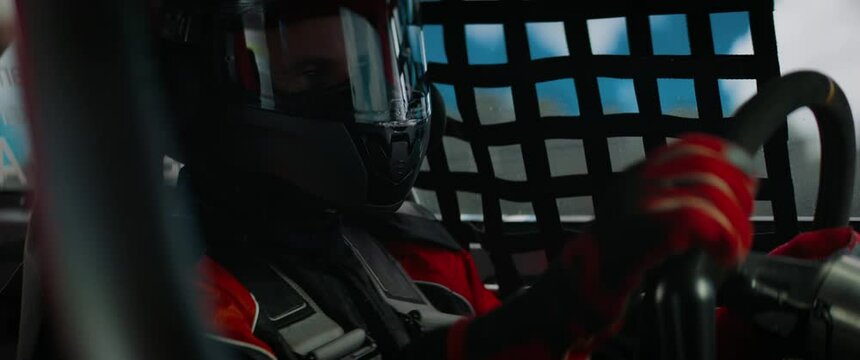 CU View of sports car driver in protective overalls racing on a speedway. Fast speed, motorsport. Daytime shot. Shot with 2x anamorphic lens