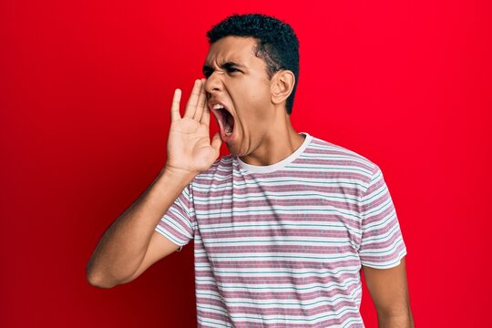 Young arab man wearing casual clothes shouting and screaming loud to side with hand on mouth. communication concept.