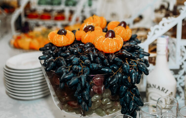 A branch of blue grapes is decorated with tangerines.