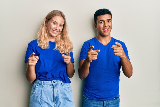 Young interracial couple wearing casual clothes pointing fingers to camera with happy and funny face. good energy and vibes.
