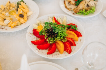 Slicing yellow and red tomatoes is decorated with lettuce.