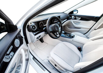 The car is inside. The interior of a prestigious modern car. Front seats with steering wheel, dashboard and display. white leather interior with black dashboard. on white background