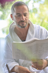 Portrait of a man wearing a bathrobe and reading the morning news  on a newspaper