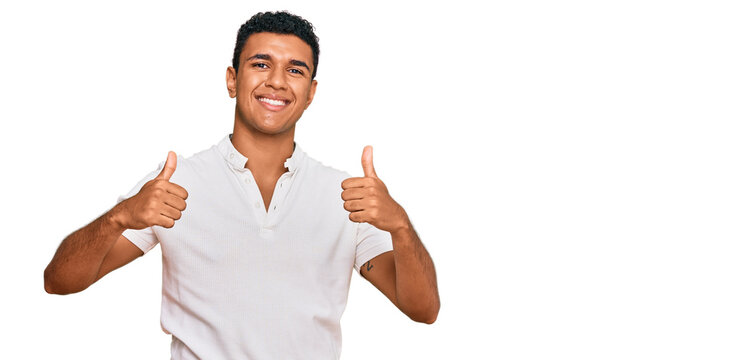 Young arab man wearing casual clothes success sign doing positive gesture with hand, thumbs up smiling and happy. cheerful expression and winner gesture.