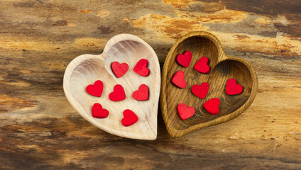 Two wooden hearts with small red hearts inside on a natural wooden background . Valentine's Day. Horizontal orientation.