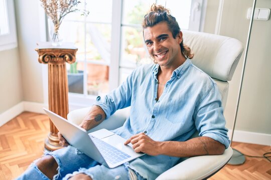Young hispanic man smiling happy using laptop at home