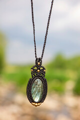 Beautiful necklace in boho style with labradorite mineral stone on natural blury landscape background