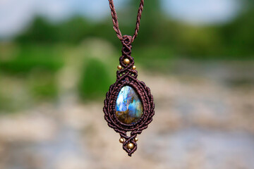 Beautiful necklace in boho style with labradorite mineral stone on natural blury landscape background