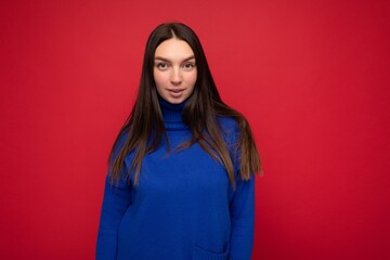 Young sexy attarctive beautiful brunette woman with sincere emotions isolated on background wall with copy space wearing casual trendy blue sweater