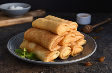 Thin pancakes with cottage cheese on a dark concrete background. Platbands. National, traditional...