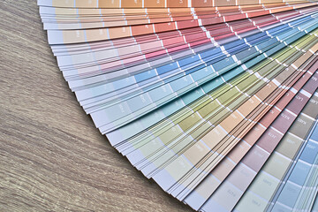 Color wheel palette for choosing paint tone. Various colors on wooden table background with copy...