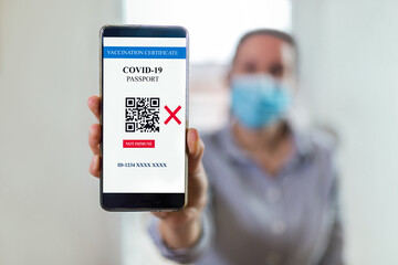 Vaccination, disease immunity passport, health and surveillance concepts. Smartphone displaying a not imunne digital vaccination certificate for COVID-19.