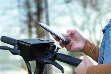 Studentin in Jeans Jacke bezahlt mit Smartphone für E Scooter