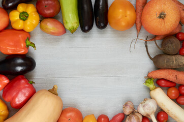 Food background with copy space for text. Fresh organic vegetables: carrots, garlic, eggplants, zucchini, beet around gray table. Raw ingredients for veggie healthy or diet dish. Top view