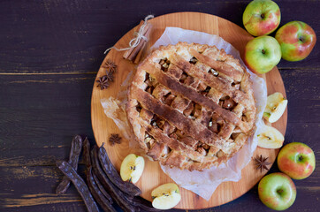 Apple pie with spices on the brown wooden board. Apple pie decorated with sliced fresh apples,...