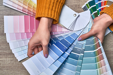 Color wheel for choosing paint tone. Hands of female interior designer working with palette for...