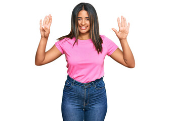 Young latin girl wearing casual clothes showing and pointing up with fingers number nine while...