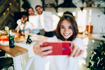Cheerful group of friends taking selfie at home while celebrating Christmas