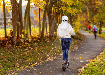 Grauhaarige Weißhaarige Frau fährt E Scooter in Park in Helm