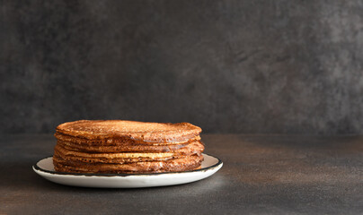 Stack of pancakes on the plate on a dark background. Thin pancakes. Good morning.